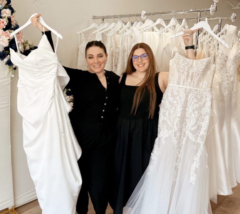 Two bridal stylists holding a bridal gowns on a hanger