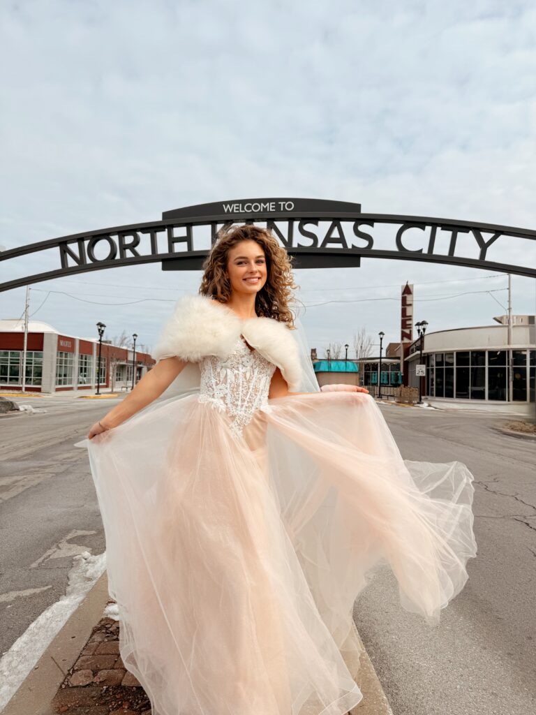 women wearing a blush bridal gown standing near North Kansas City Signage