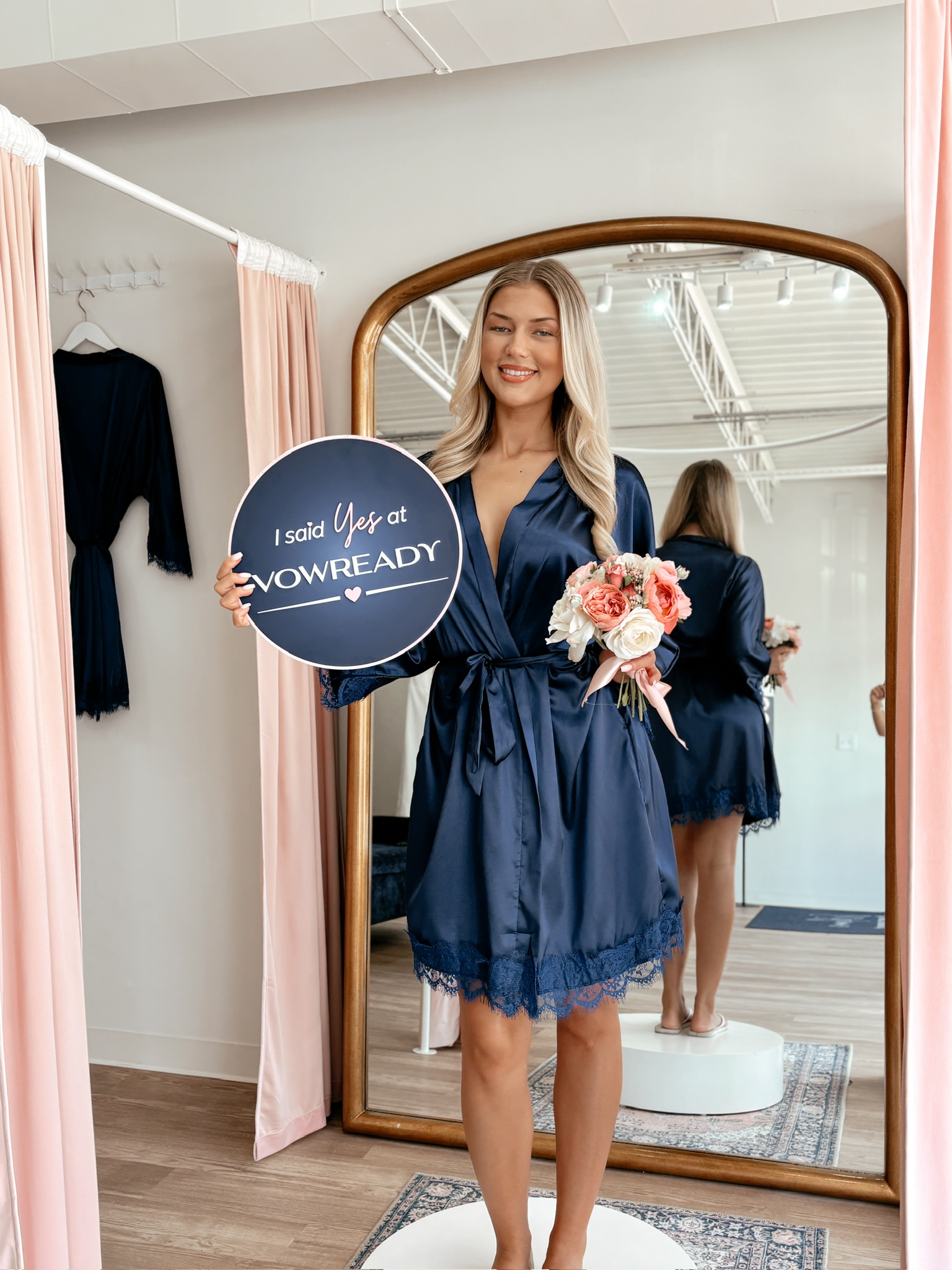 happy bride wearing an navy blue robe while holding a I say yes signage