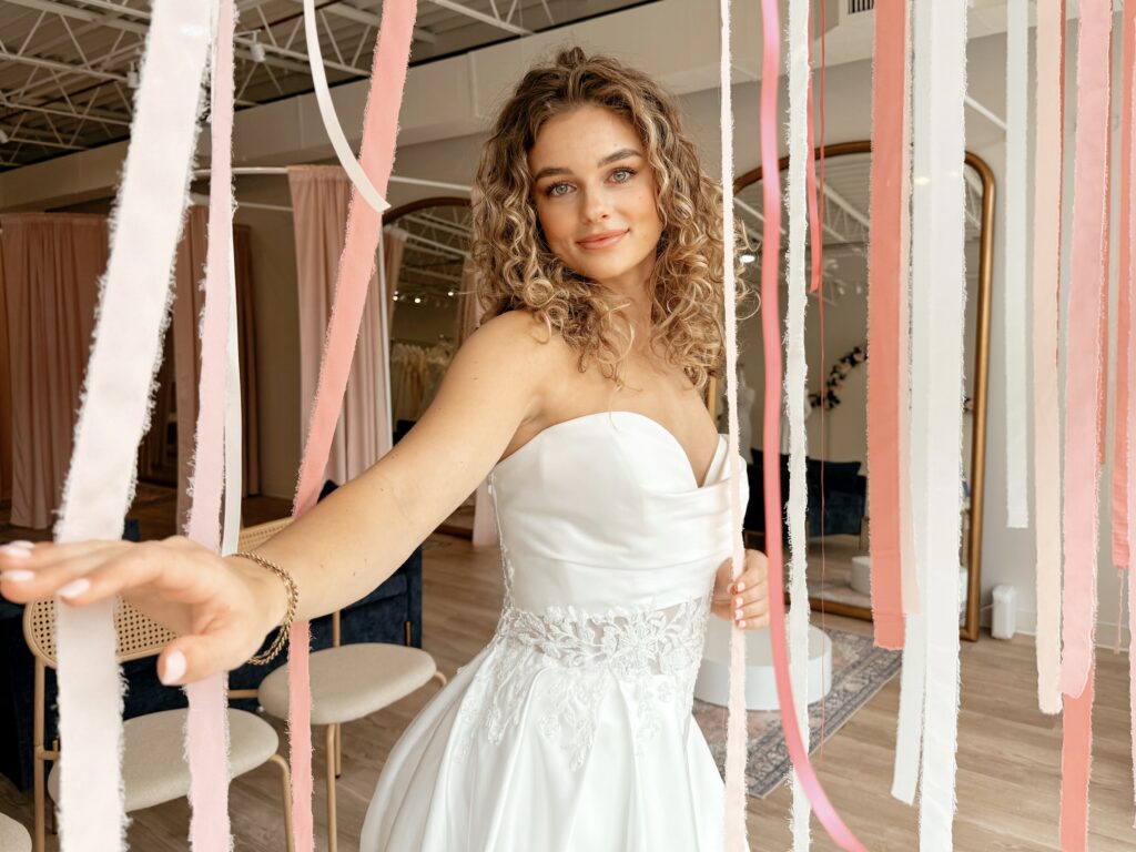 Bride wearing a strapless A-line wedding dress with lace appliqués in a private bridal suite at Savvy Bridal.