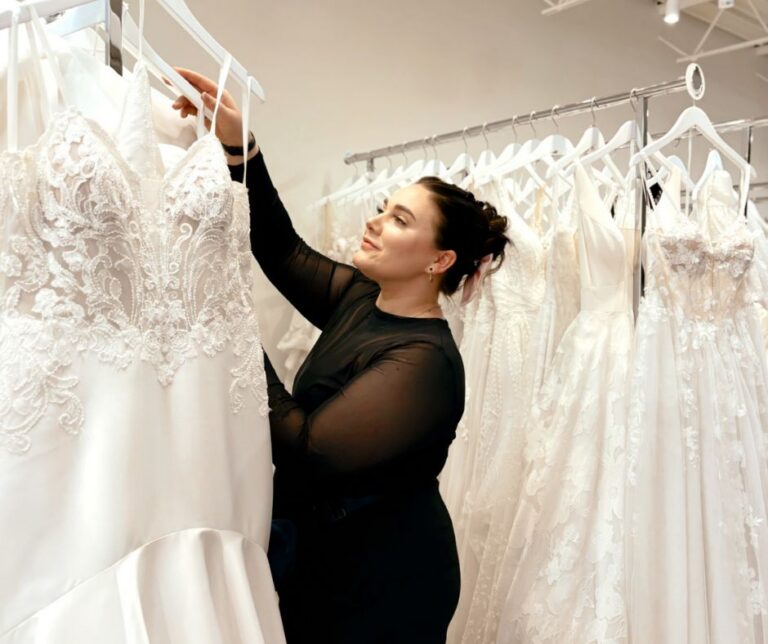 Bridal stylist browsing a rack of wedding dresses inside Vow Ready bridal boutique.