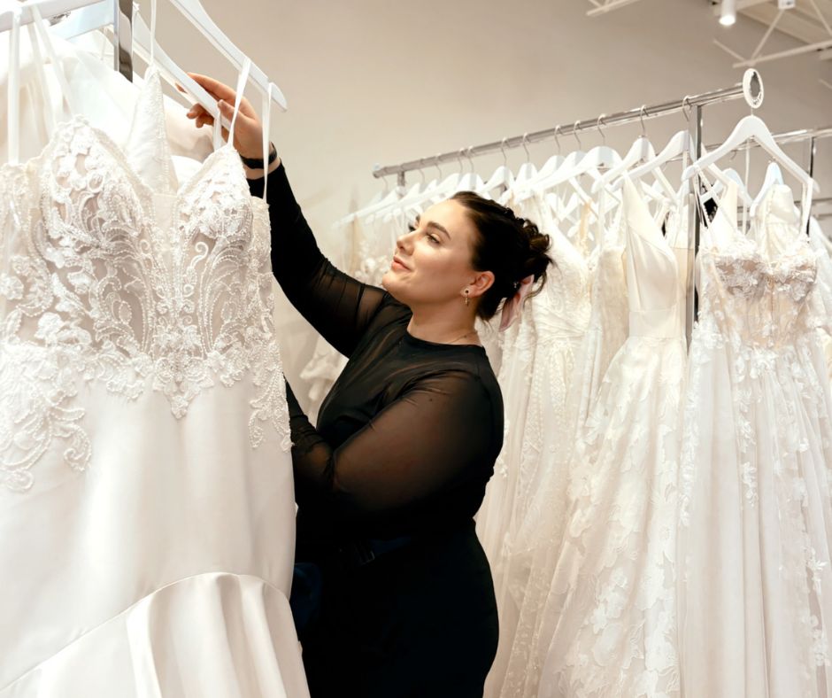 Bridal stylist browsing a rack of wedding dresses inside Vow Ready bridal boutique.